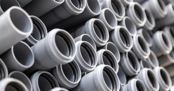 A large stack of long tubes of grey, plastic piping used for water lines in residential plumbing systems