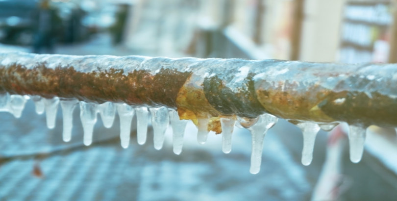 Icicles hanging from a frozen pipe in winter