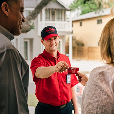 Mr. Rooter professional handing a customer his business card.