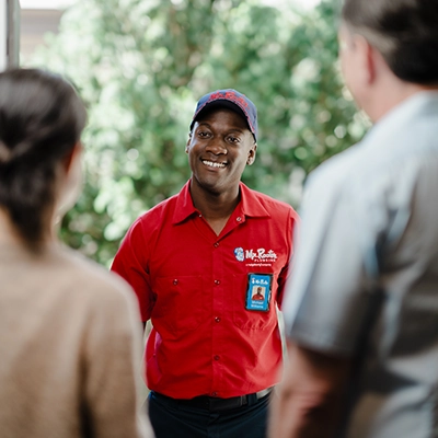 Mr. Rooter professional greeting customers at their front door.