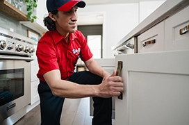 Mr. Rooter professional opening a lower kitchen cabinet.