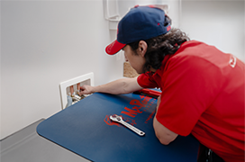 Mr. Rooter technician fixing a water valve in a laundry room.