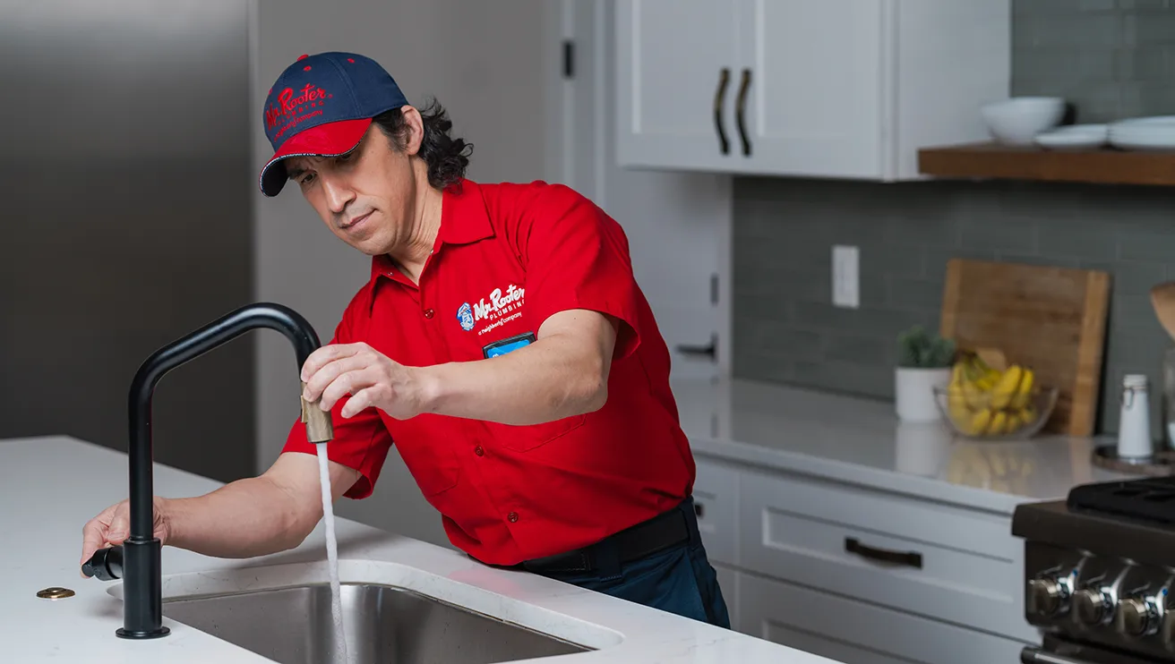 Mr. Rooter professional fixing a sink faucet.