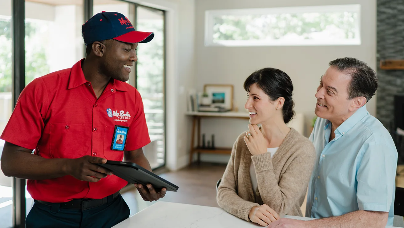 Mr. Rooter technician using a tablet to show a couple their service options.