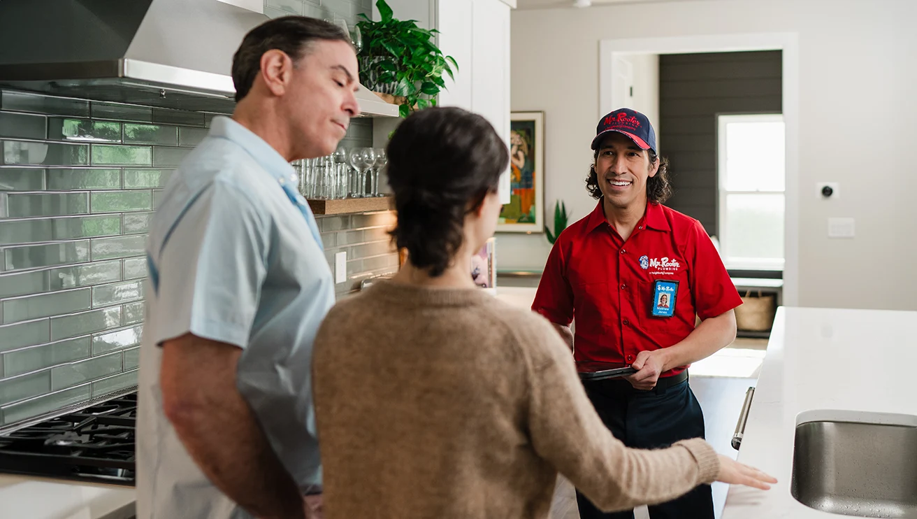 Mr. Rooter technician showing customers plumbing leak service options.