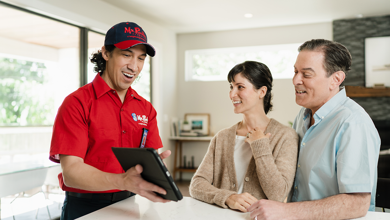 Mr. Rooter technician using a tablet to show a couple their service options.