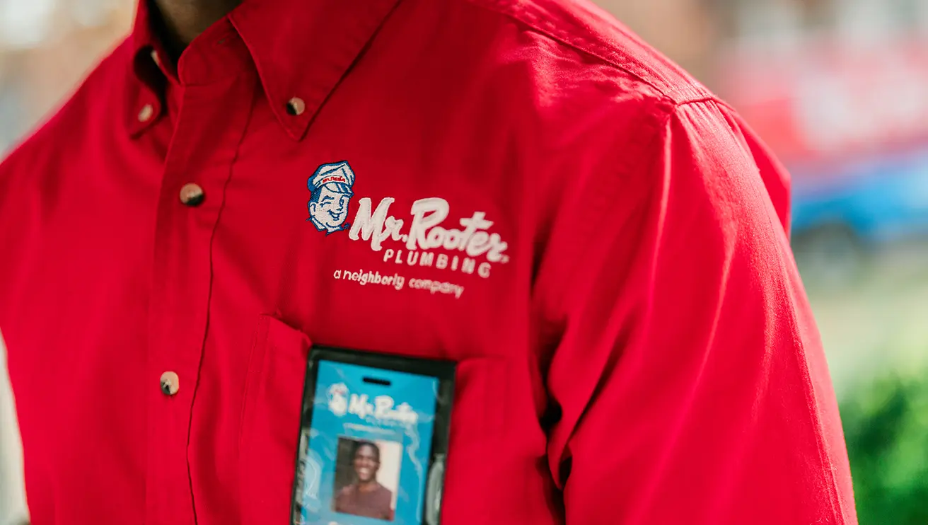 Close up image of a red Mr. Rooter branded shirt and technician name tag.