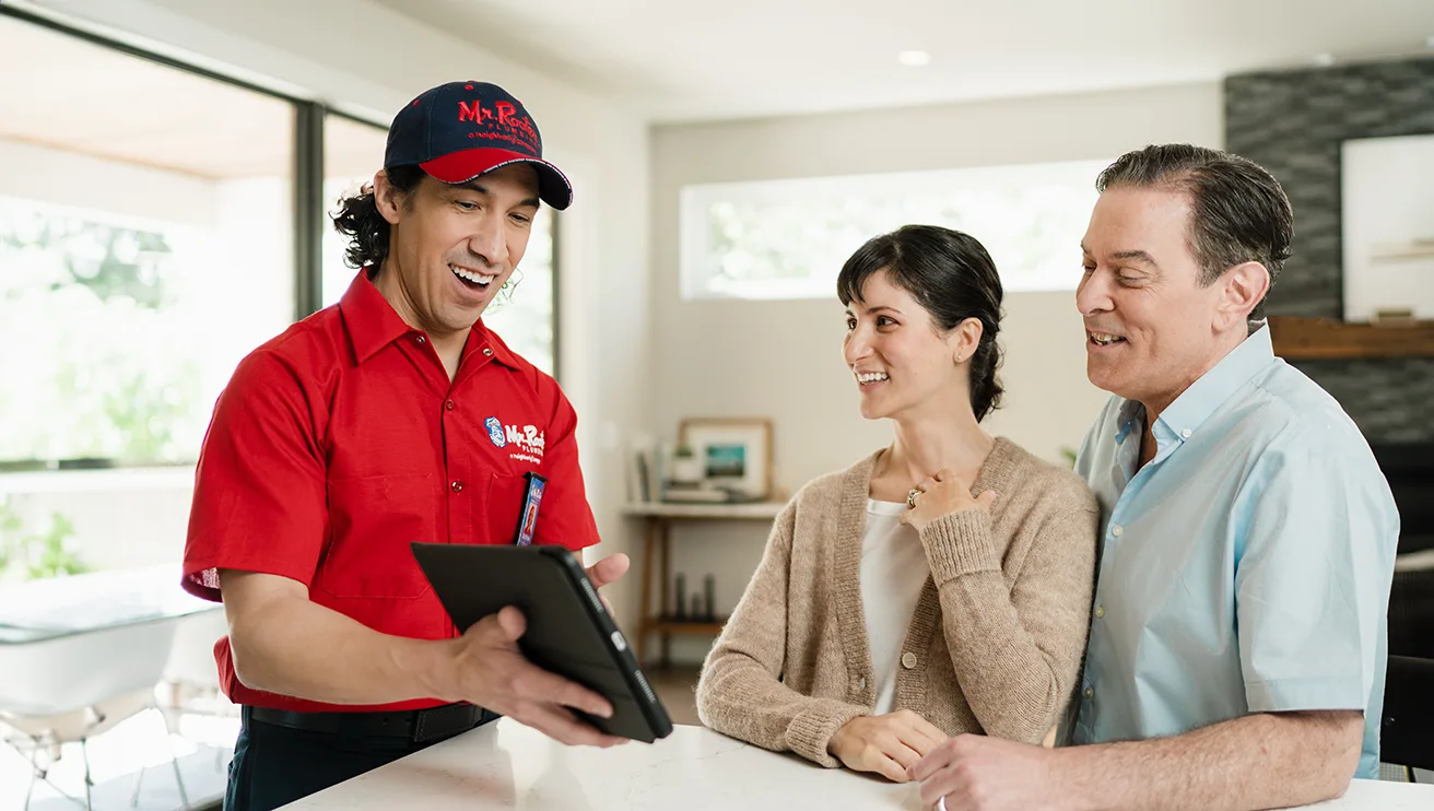 Mr. Rooter technician showing two customers a tablet screen.