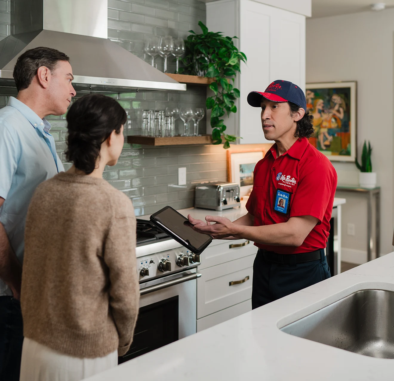 Mr. Rooter technician showing customers emergency plumbing service options on a tablet.