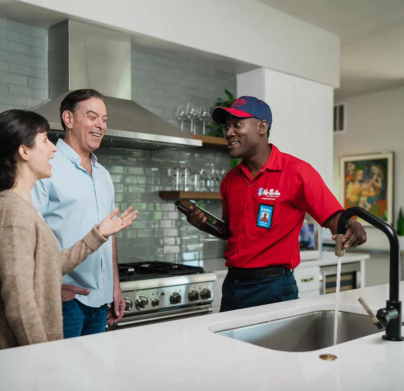 Mr. Rooter technician speaking with customers in their kitchen.