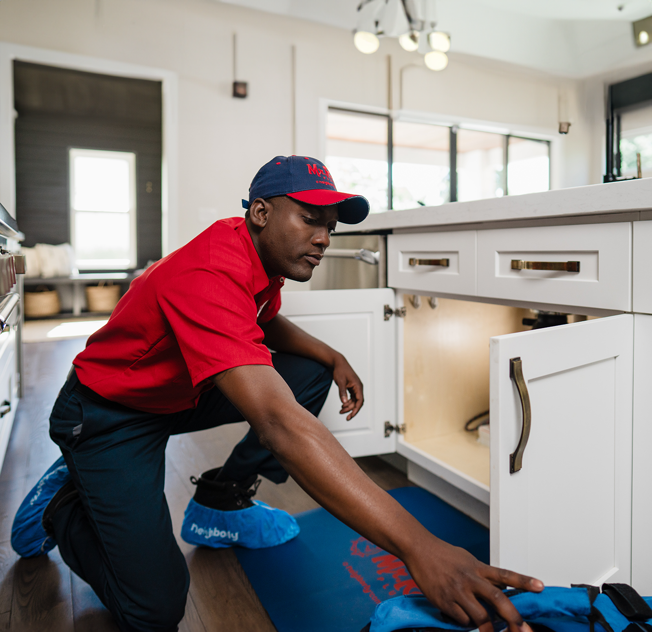 A Mr. Rooter technician working on a customer's garburator under their sink.