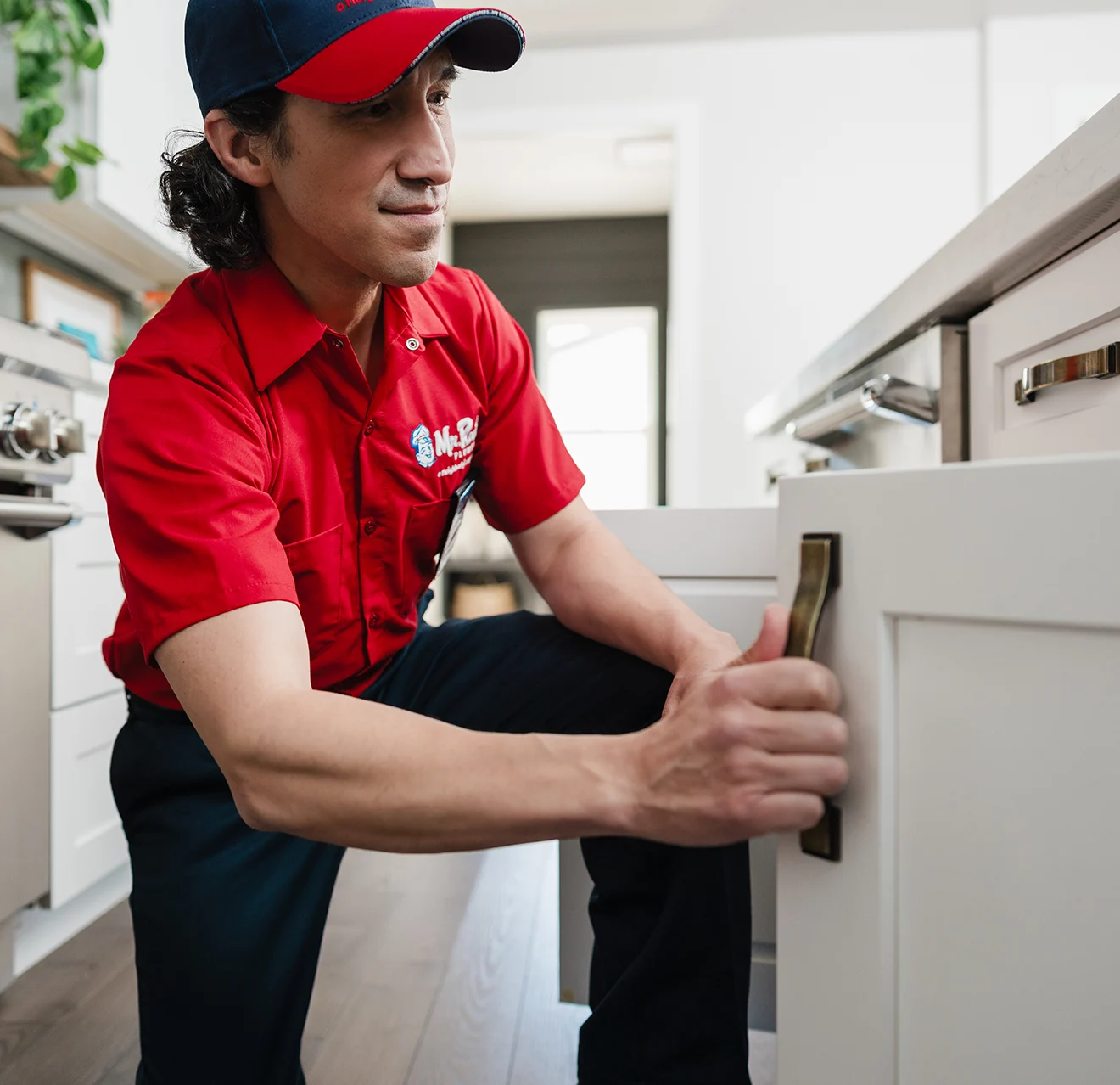 Mr. Rooter technician opening a cabinet door.