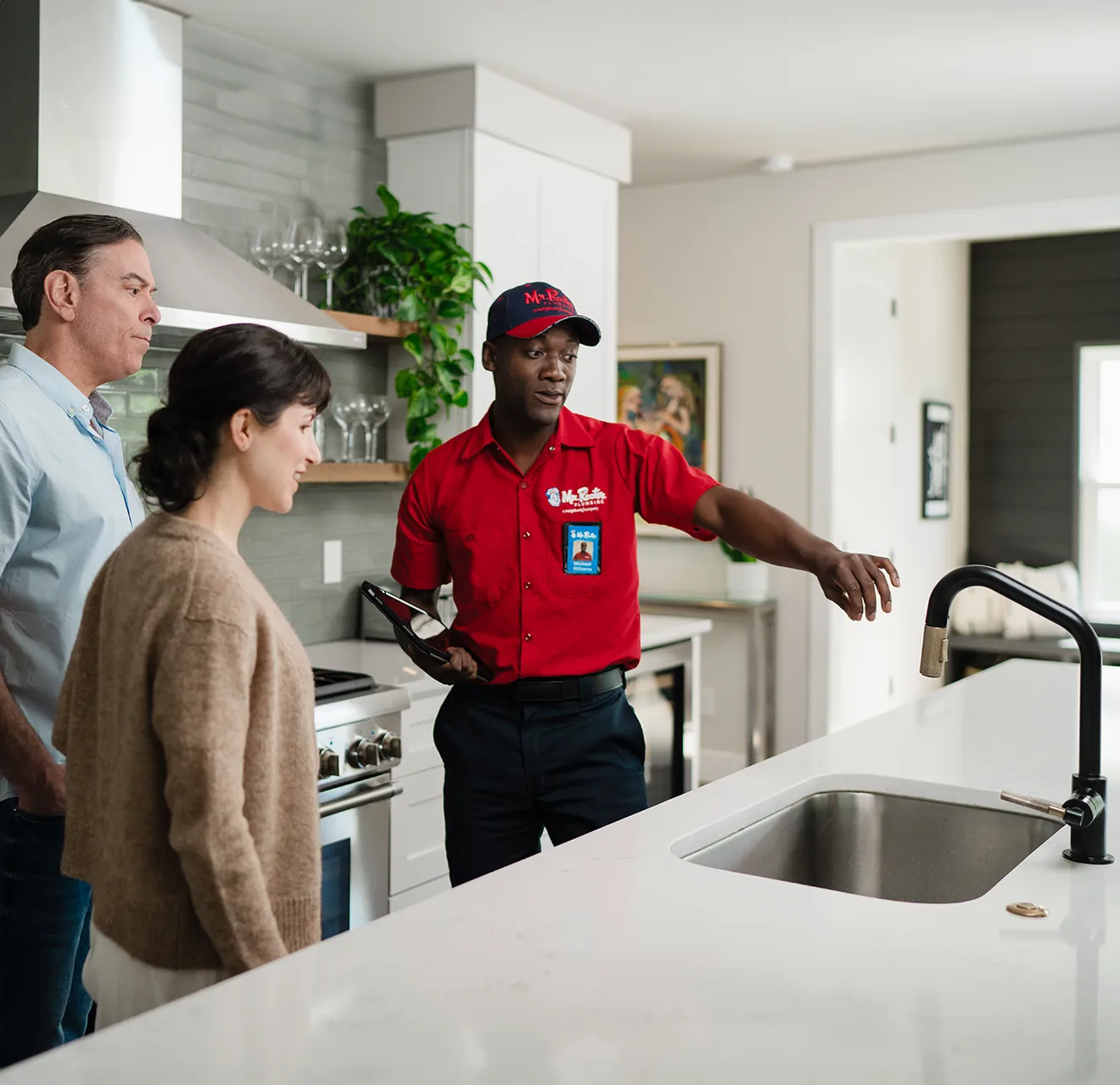 Mr. Rooter technician showing customers a kitchen sink repair.