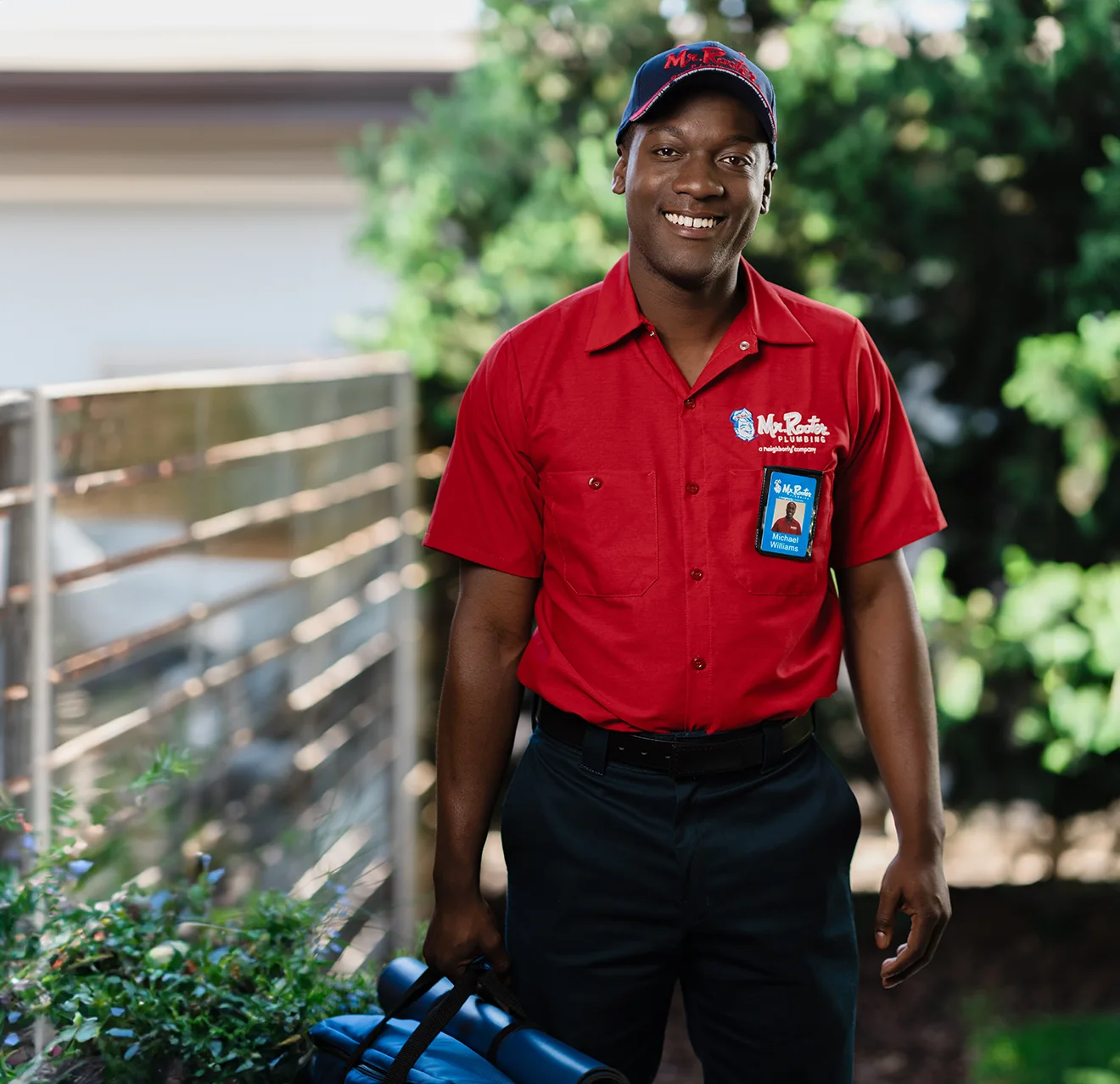 Smiling Mr. Rooter professional on the exterior of a home.