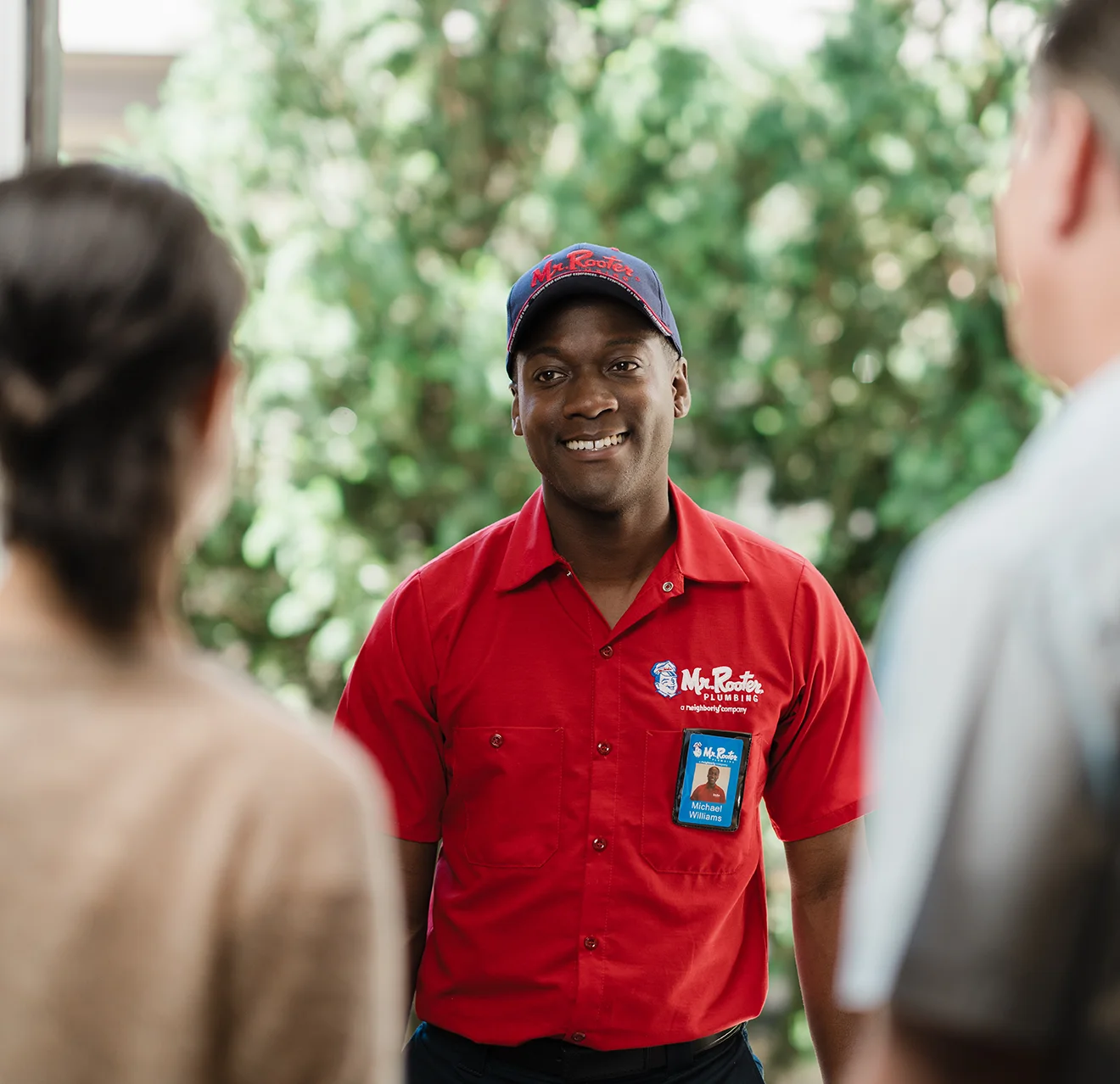 Two customers greeting a Mr. Rooter technician at their front door.