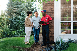 Mr. Rooter professional speaking with two customers outside of their home.
