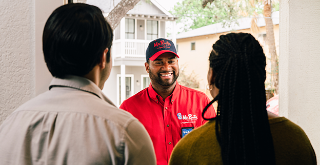 Two customers greeting a Mr. Rooter technician at their front door.