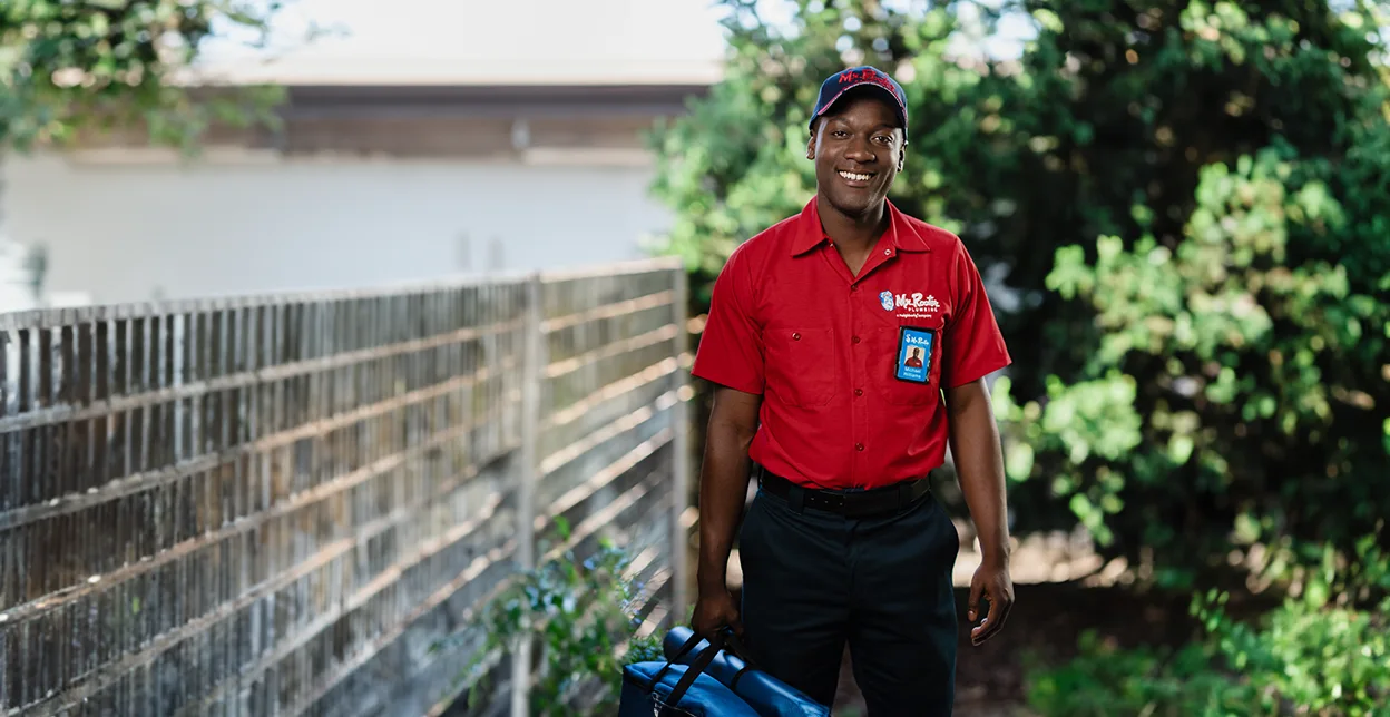 Smiling Mr. Rooter technician standing outside of a building.