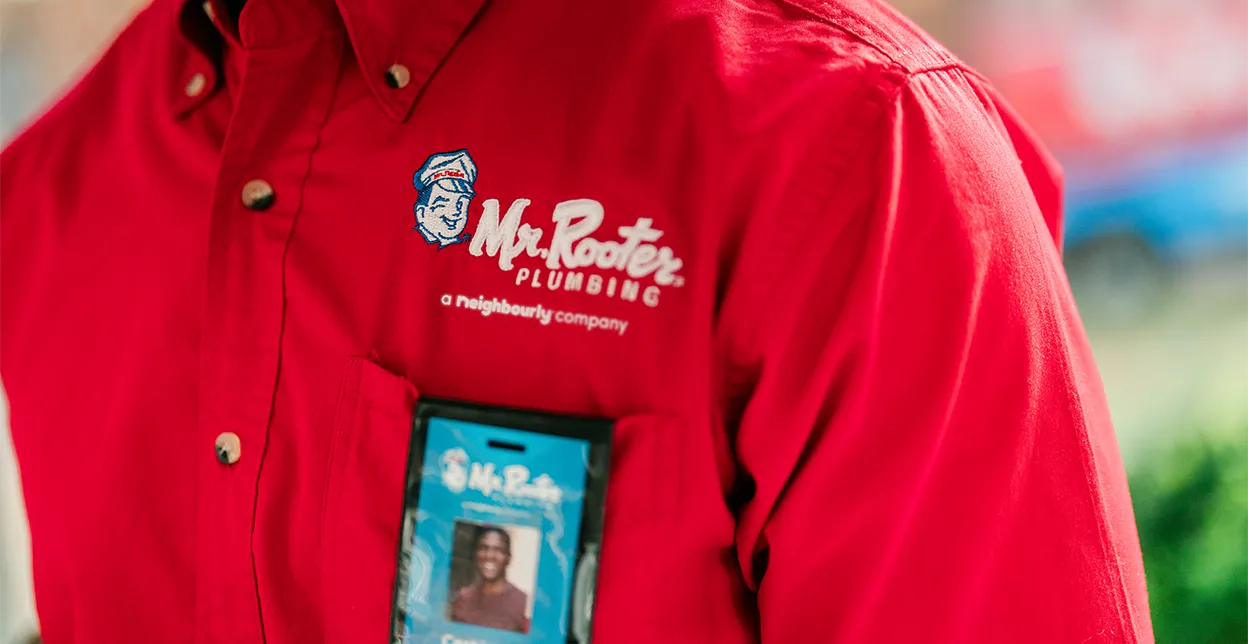 Close up angle of a technician's red Mr. Rooter work shirt with name tag.