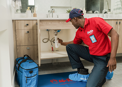 Mr. Rooter Plumbing technician working underneath a sink.