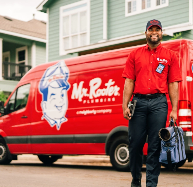 Smiling Mr. Rooter technician in front of the vehicle.