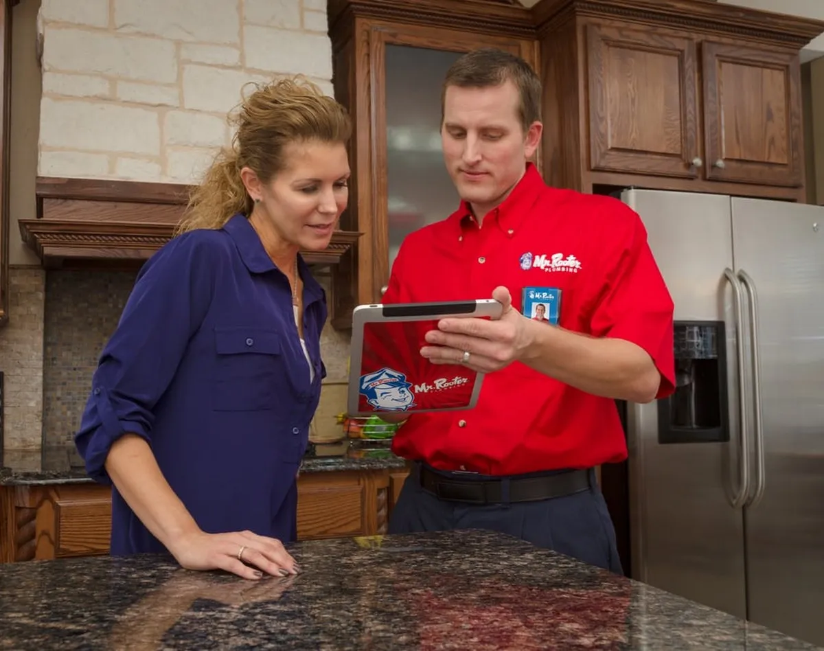 Mr. Rooter Plumbing technician explaining clogged drain services to Edmonton homeowner.