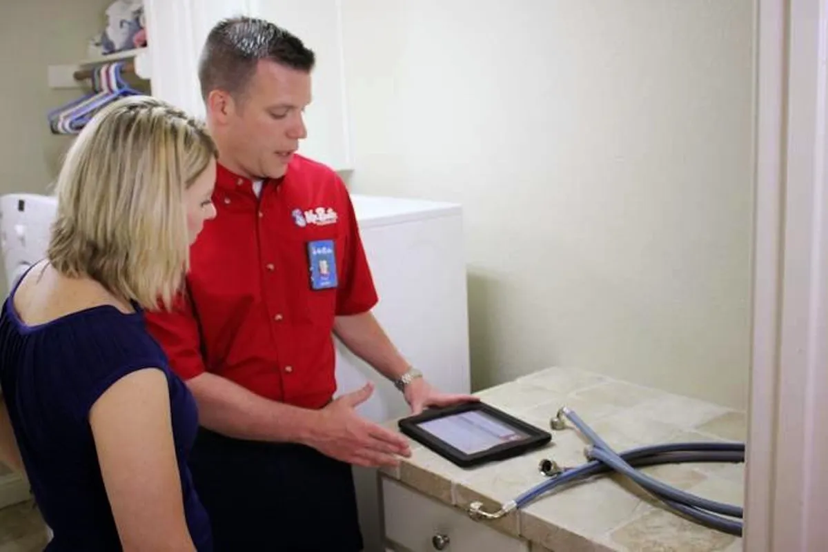  A plumber from Mr. Rooter Plumbing using an electronic tablet to show a woman information about her water line repairs.