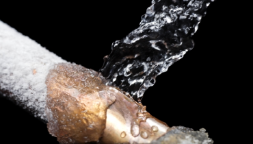 Busted water pipe covered with ice and with water shooting out