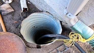 An exterior sump pump installed next to a house.