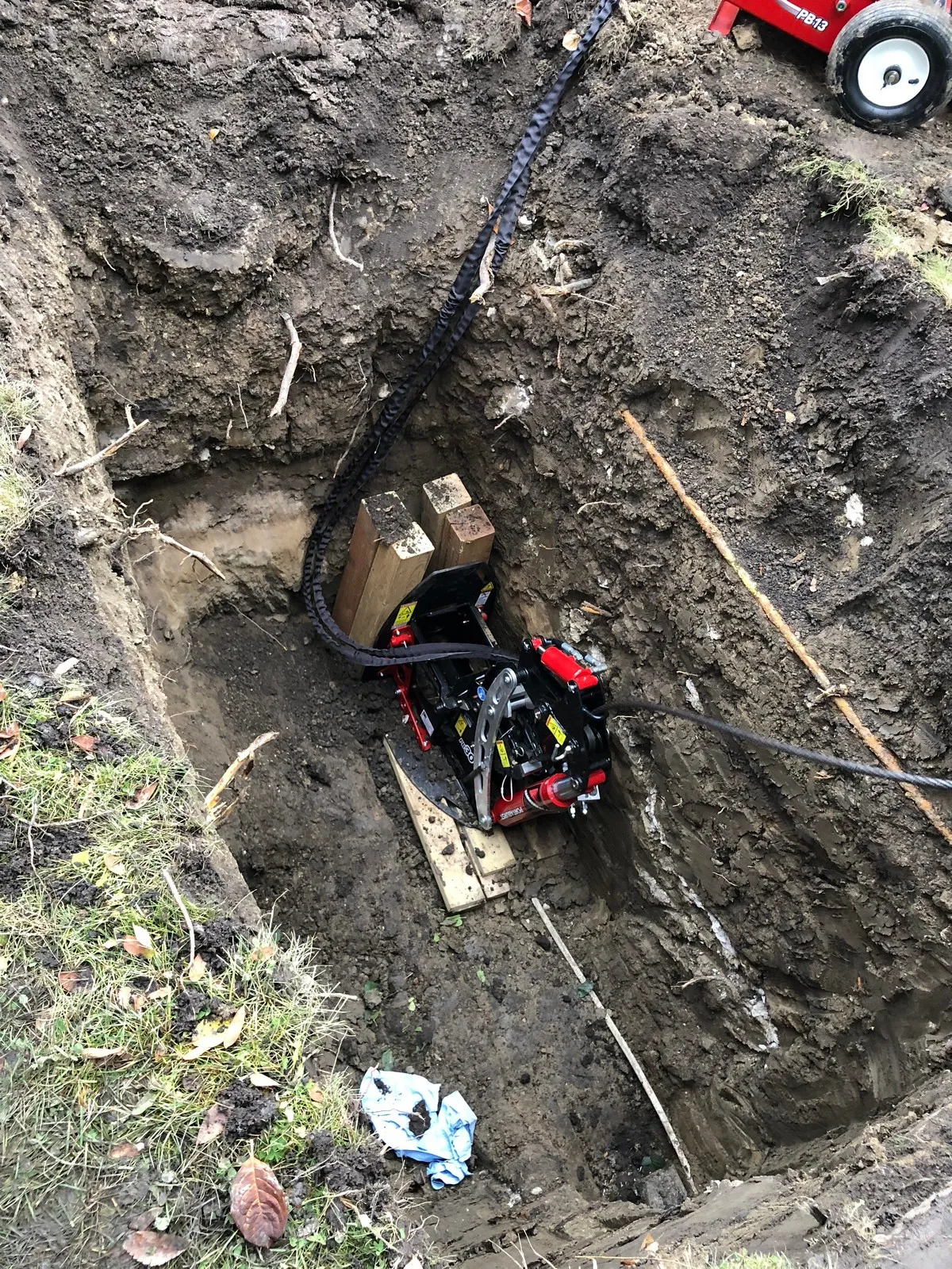 A rectangular hole in the ground with a device placed inside to facilitate sewer pipe repairs.