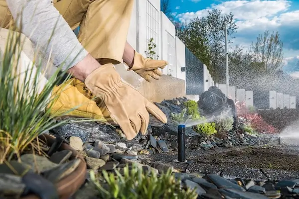 An irrigation sprinkler system expert tending to an above-ground sprinkler